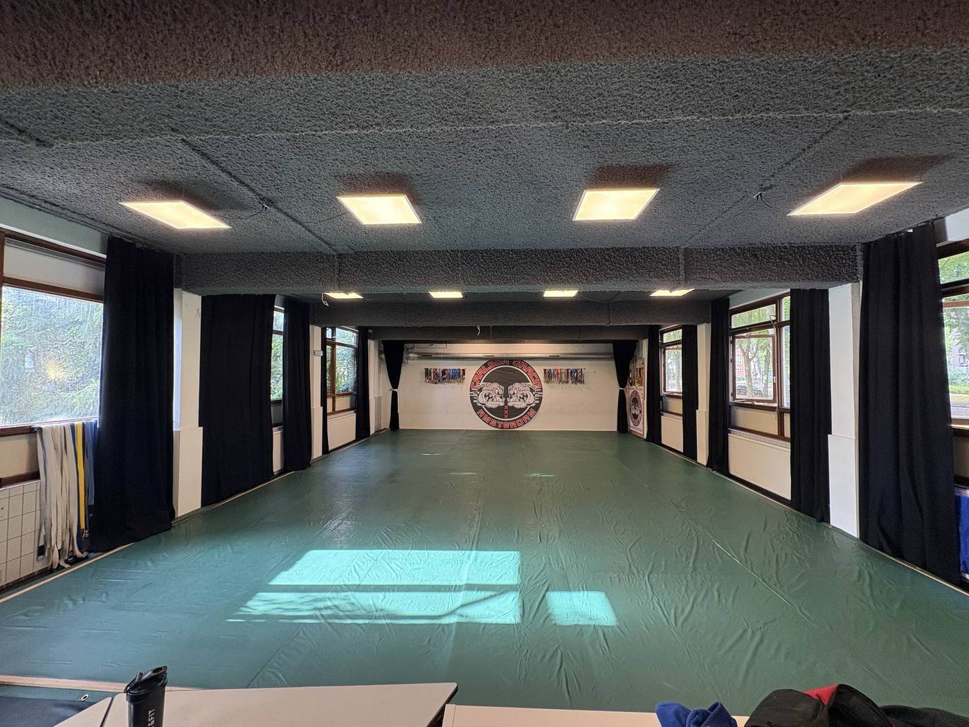 The training floor at Carlson Gracie Amsterdam: 120 square metres of mats with windows along both walls.